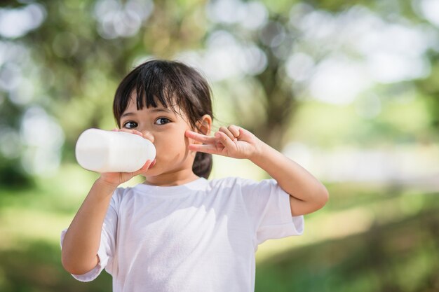 Cute asian little child girl is drinking a milk, soft focus