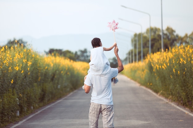 Cute asian little girl playing with wind turbine and riding on father's shoulders