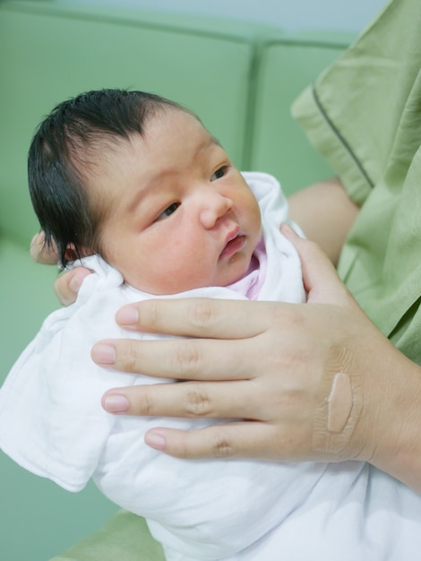 Cute Asian little newborn baby Being carried by hand of mother