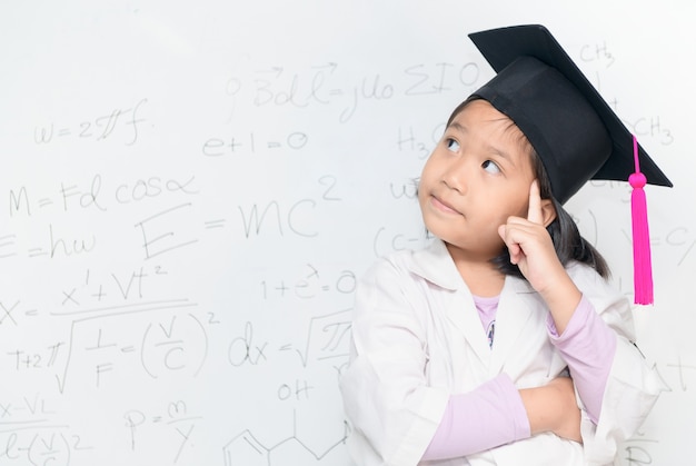 cute asian scientist girl wear graduation hat thinking on white borad with scientific equation, scie