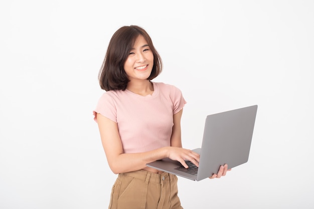 Cute Asian teen woman is working with computer on white wall