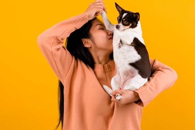 Cute Asian woman with his chihuahua chihuahua dog lover The happiness of a girl who loves his dog The love of people and cute dogs photo shoot in orange studio