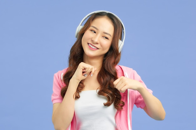 Cute asian young woman in white wireless headphones dancing near copy space