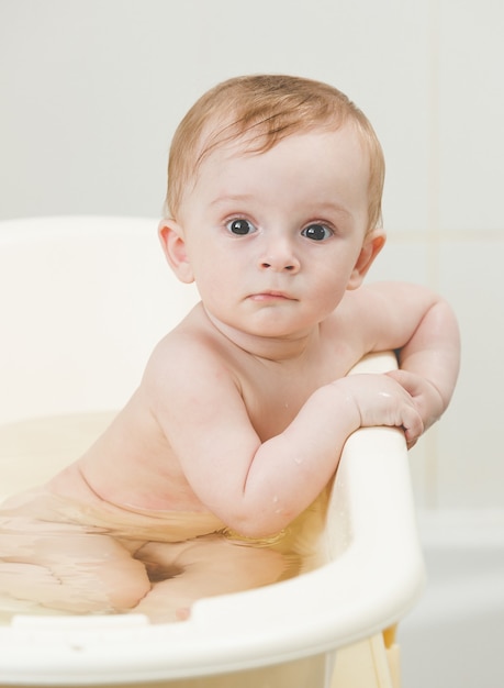 Cute baby boy bathing and looking at camera