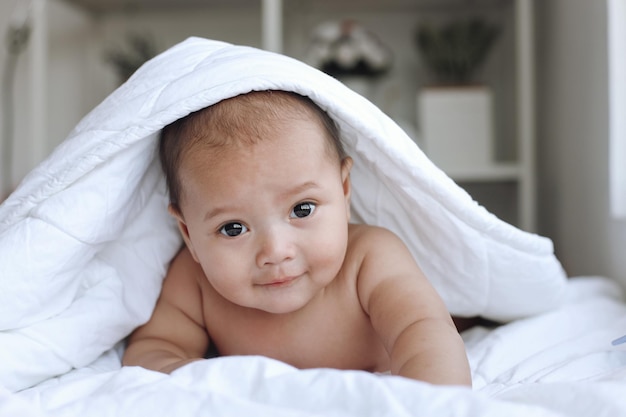 Cute baby boy crawling on the bed body covered by the blanket Happy moments