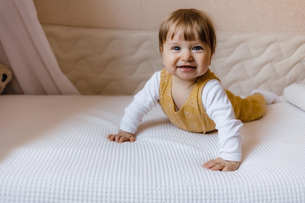 Cute baby boy lying on white sheet at home boy sitting on the bed