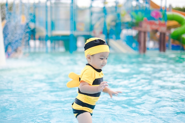 Cute baby boy on yellow swimsuit play in beautiful blue swimming pool