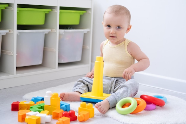 Cute baby girl playing in colorful pyramid on floor at home Early childhood development