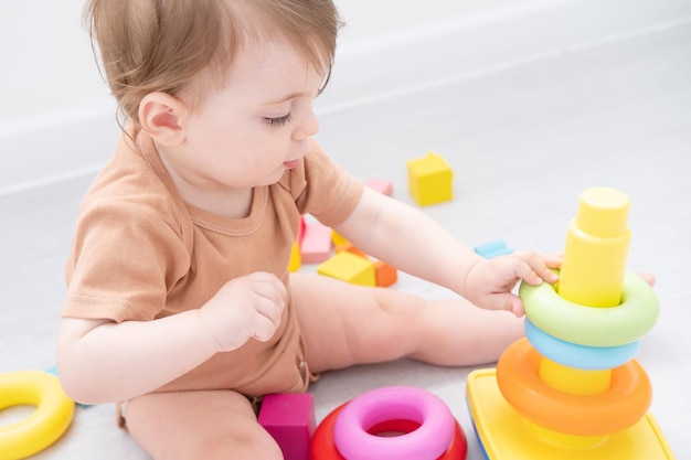 cute baby girl playing with pyramid and wooden toys at home early children development