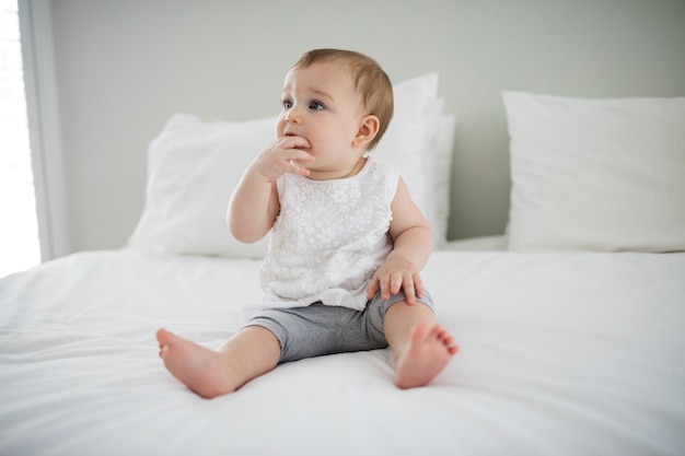 Cute baby girl relaxing on bed in bedroom