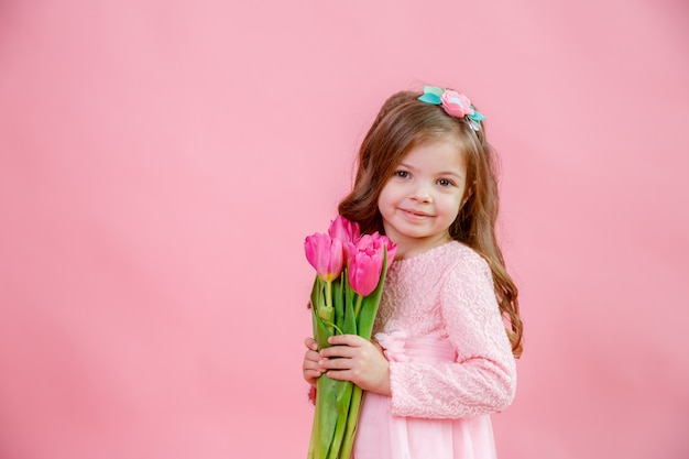 Cute baby girl with a bouquet of tulips in her hands