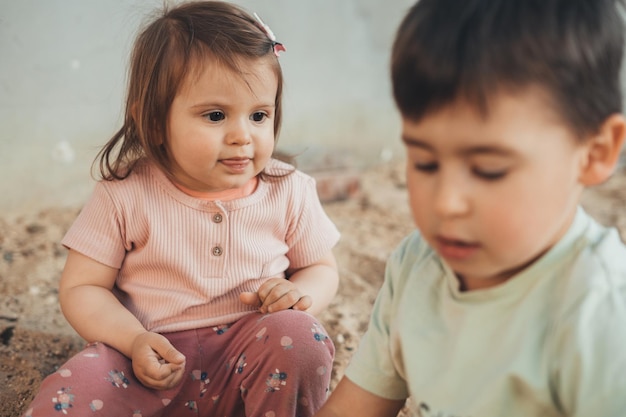 A cute baby girl with her brother playing with sand on playground in the weekends Plays Outdoor activities joint pastime recreation concept