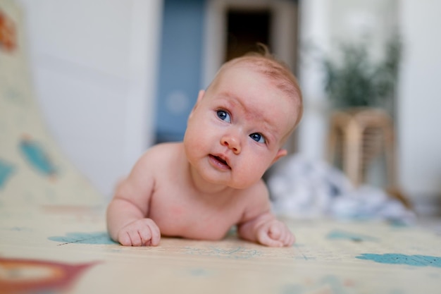 A cute baby is lying on his stomach. A three- month-old baby