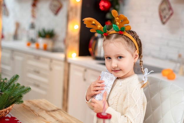 Cute baby in a light sweater and headband with reindeer horns