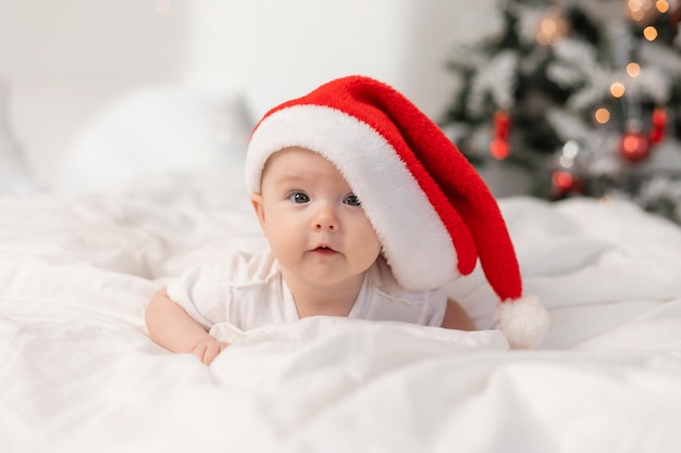 cute baby in Santa hat at home in bed. The first New Year. Christmas Gift