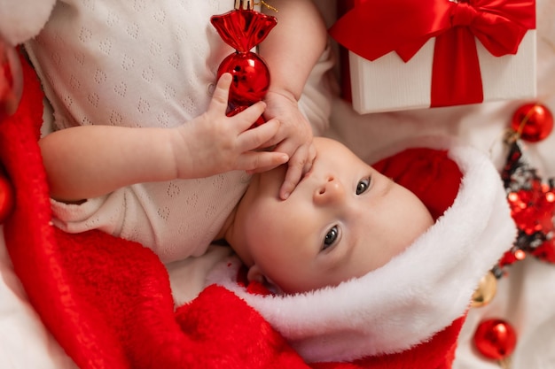 cute baby in Santa hat at home in bed. The first New Year. Christmas Gift