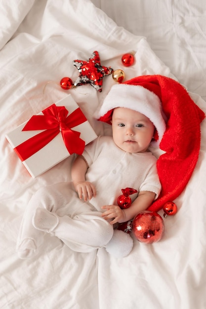 cute baby in Santa hat at home in bed. The first New Year. Christmas Gift