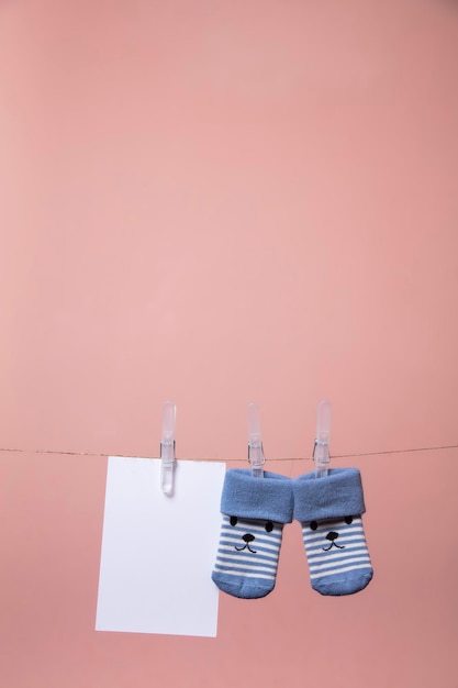 Cute baby socks with a face and blank card hanging on a clothes line