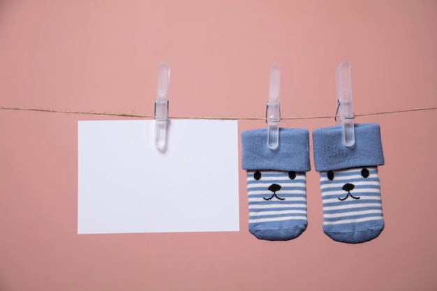 Cute baby socks with a face and blank card hanging on a clothes line