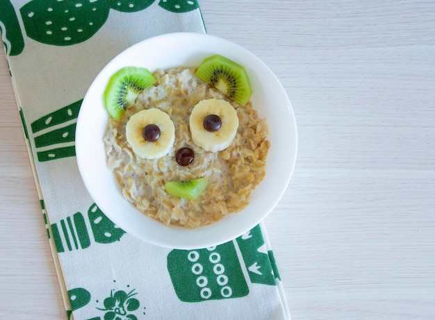 Cute bear face made of oatmeal banana kiwi and chocolate Children's breakfast