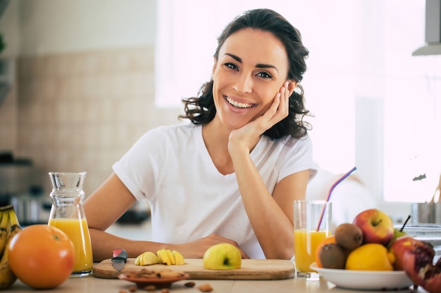 Cute beautiful and happy young brunette woman in the kitchen