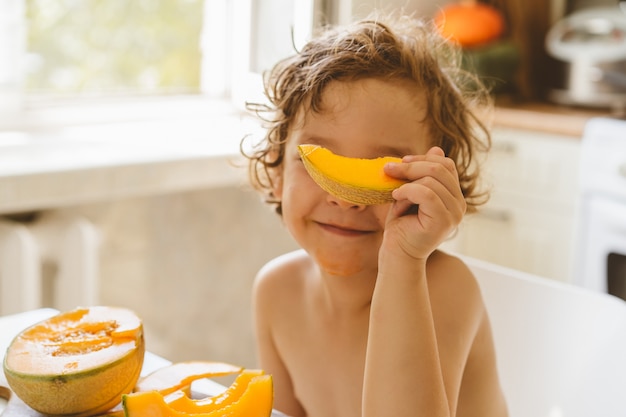 Cute beautiful little boy eating fresh melon