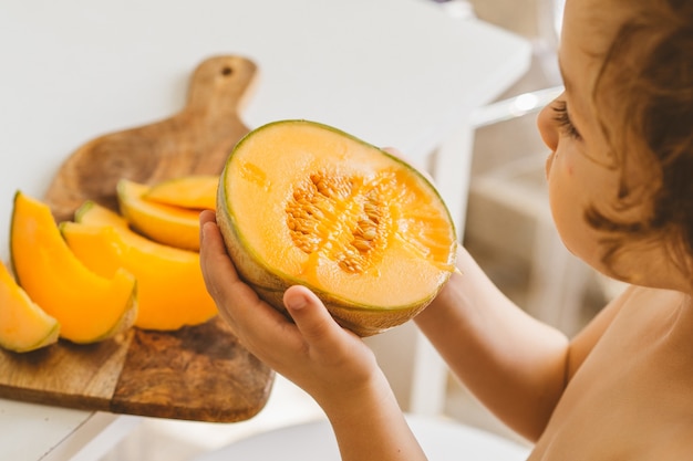 Cute beautiful little boy eating fresh melon