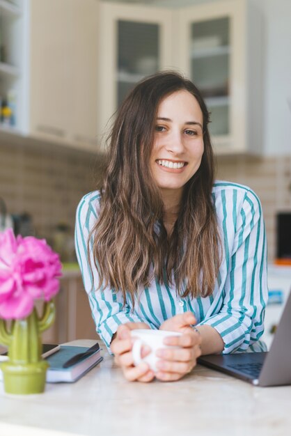 Cute and beautiful young woman staying at home and drinking cup of coffee