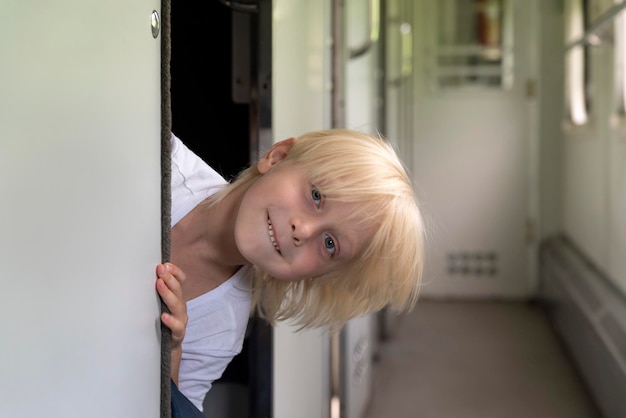 Cute blond boy looks out of compartment in railway carriage Traveling with children