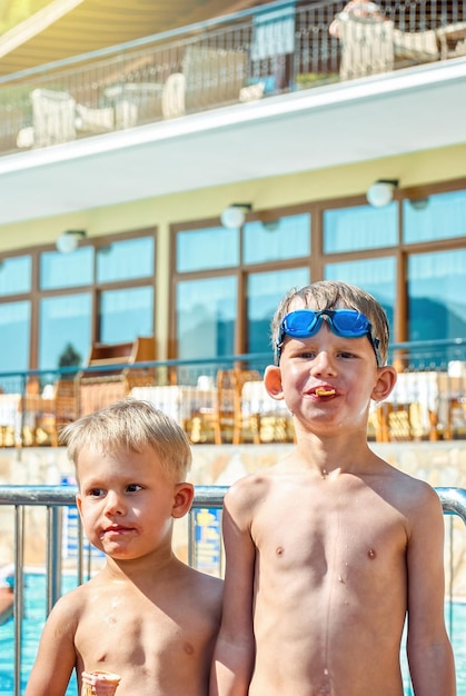 Cute blond boys eat ice cream standing near swimming pool in hotel of Marmaris