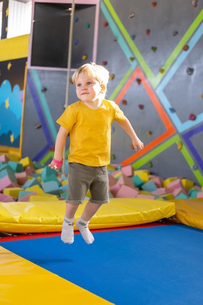 Cute blond little boy jumps in a trampoline park children activity