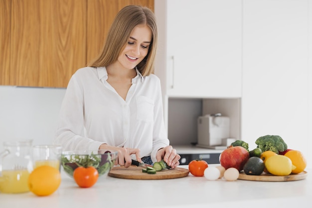 A cute blonde woman is preparing a salad in the kitchen