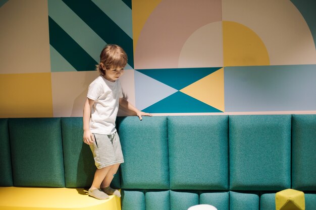 Photo cute boy in game center is balancing on soft surfaces. color therapy in children's health and training centers. organization of children's playrooms. modern children's institutions.