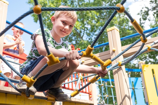 Cute boy having fun and climbing on the outdoor playground.