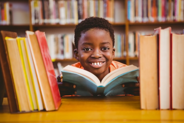 Cute boy reading book in library