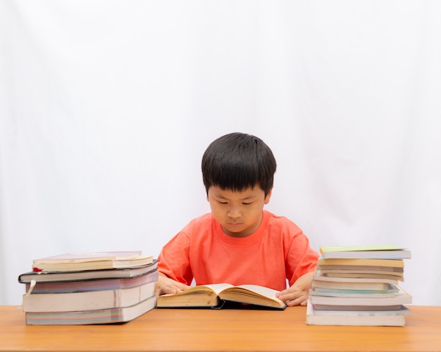 Cute a boy reading book on the table and white background,