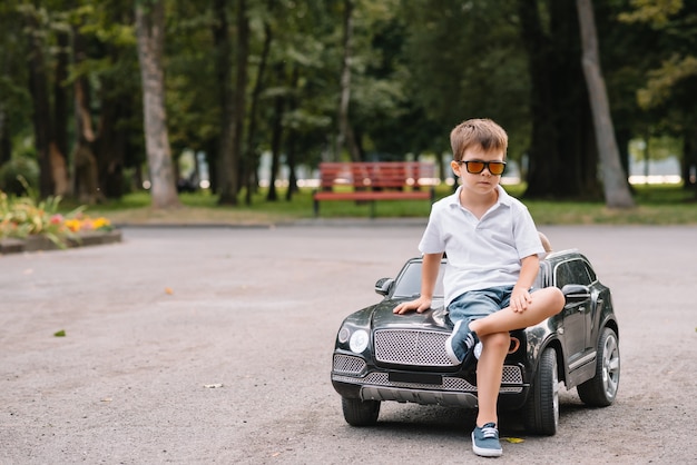 Cute boy in riding a black electric car in the park