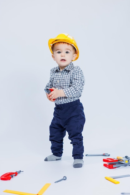 A cute boy in a shirt in the image of a builder on a white background Childhood learning work games career imitation Little daddy's helper