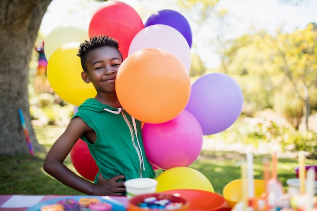 Cute boy smiling and posing next to balloon during a birthday party