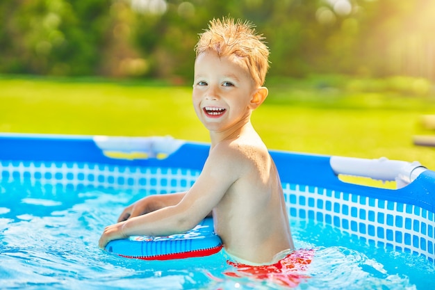 Cute boy swimming and playing in a backyard pool