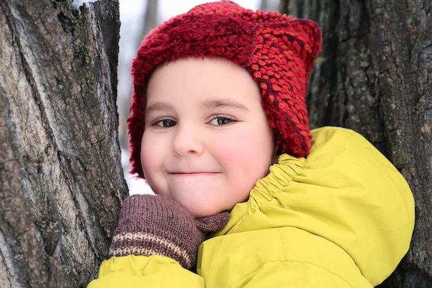 Cute boy on tree in snowy park on winter vacation