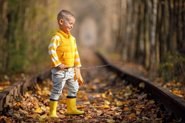 Cute boy walking on a railroad smiling autumn time love tunnel in autumn romantic place