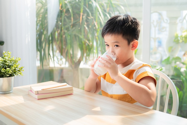 Cute boy with glass of milk sitting at a table