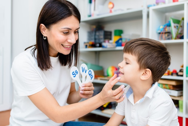 A cute boy with a speech therapist is taught to pronounce the letters, words and sounds.