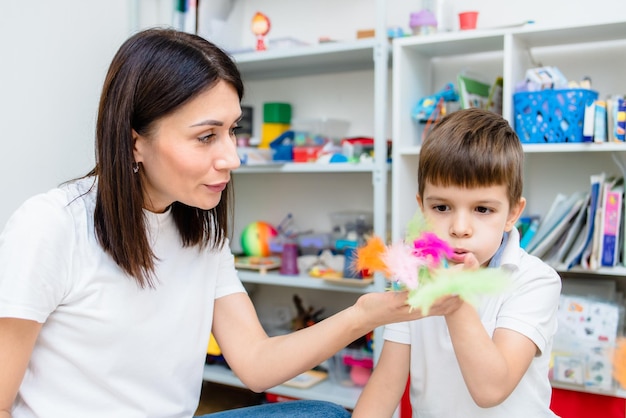 A cute boy with a speech therapist is taught to pronounce the letters words and sounds