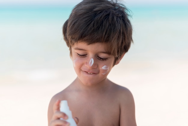 Cute boy with suncream at the beach