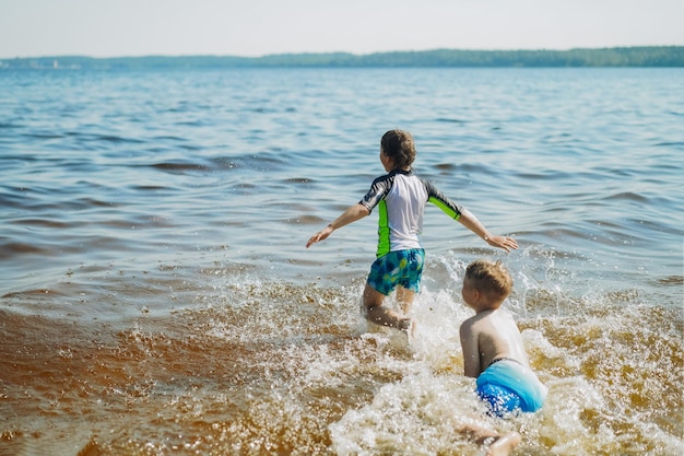 Cute  boys running into water with splashes and laughter vacation on sea side happy childhood