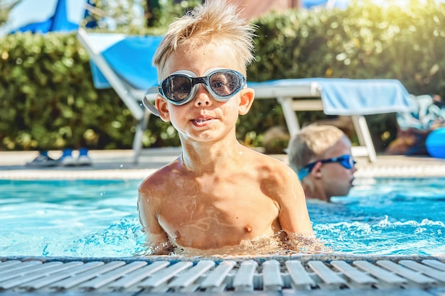 Cute brothers enjoy swimming in pool at hotel territory