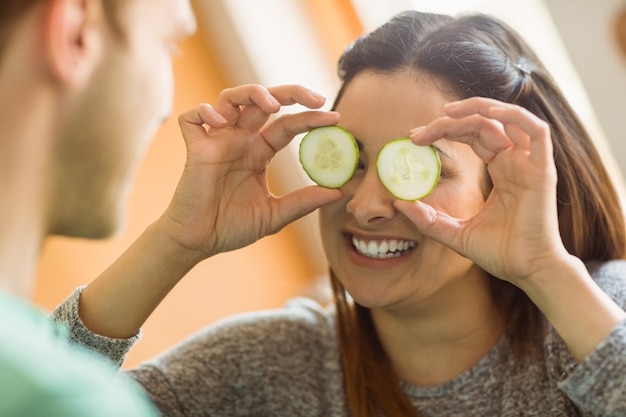 Cute brunette holding cucumber slices over eyes