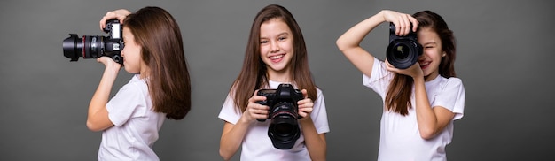 Cute brunette little girls holding an photo camera isolated on gray background